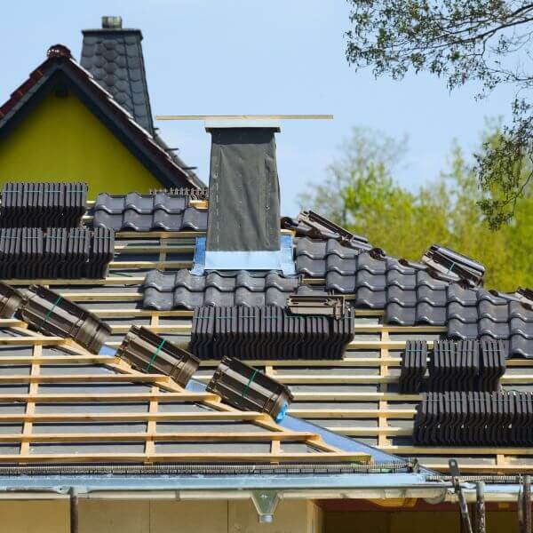 New tiled roof installation underway by Roofing Guys Central Coast showing roof battens, stacked tiles, and chimney flashing in progress. New tiled roof installation underway by Roofing Guys Central Coast showing roof battens, stacked tiles, and chimney flashing in progress.