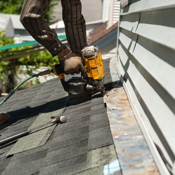 Roofer from Roofing Guys Central Coast using nail gun to carry out emergency roof repairs on a storm-damaged roof. Roofer from Roofing Guys Central Coast using nail gun to carry out emergency roof repairs on a storm-damaged roof.
