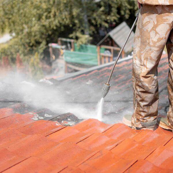 Roofing Guys Central Coast team member pressure cleaning a tiled roof as part of a residential roof restoration. Roofing Guys Central Coast team member pressure cleaning a tiled roof as part of a residential roof restoration.