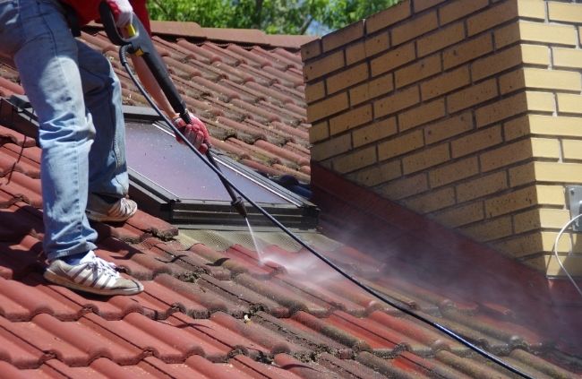 Roof cleaning underway on the Central Coast by Roofing Guys experts, washing roof tiles for a cleaner, longer-lasting finish.
