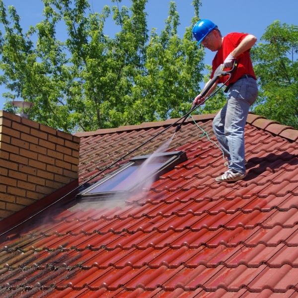 Professional roof cleaning by Roofing Guys Central Coast removing moss and dirt with high-pressure washing.
